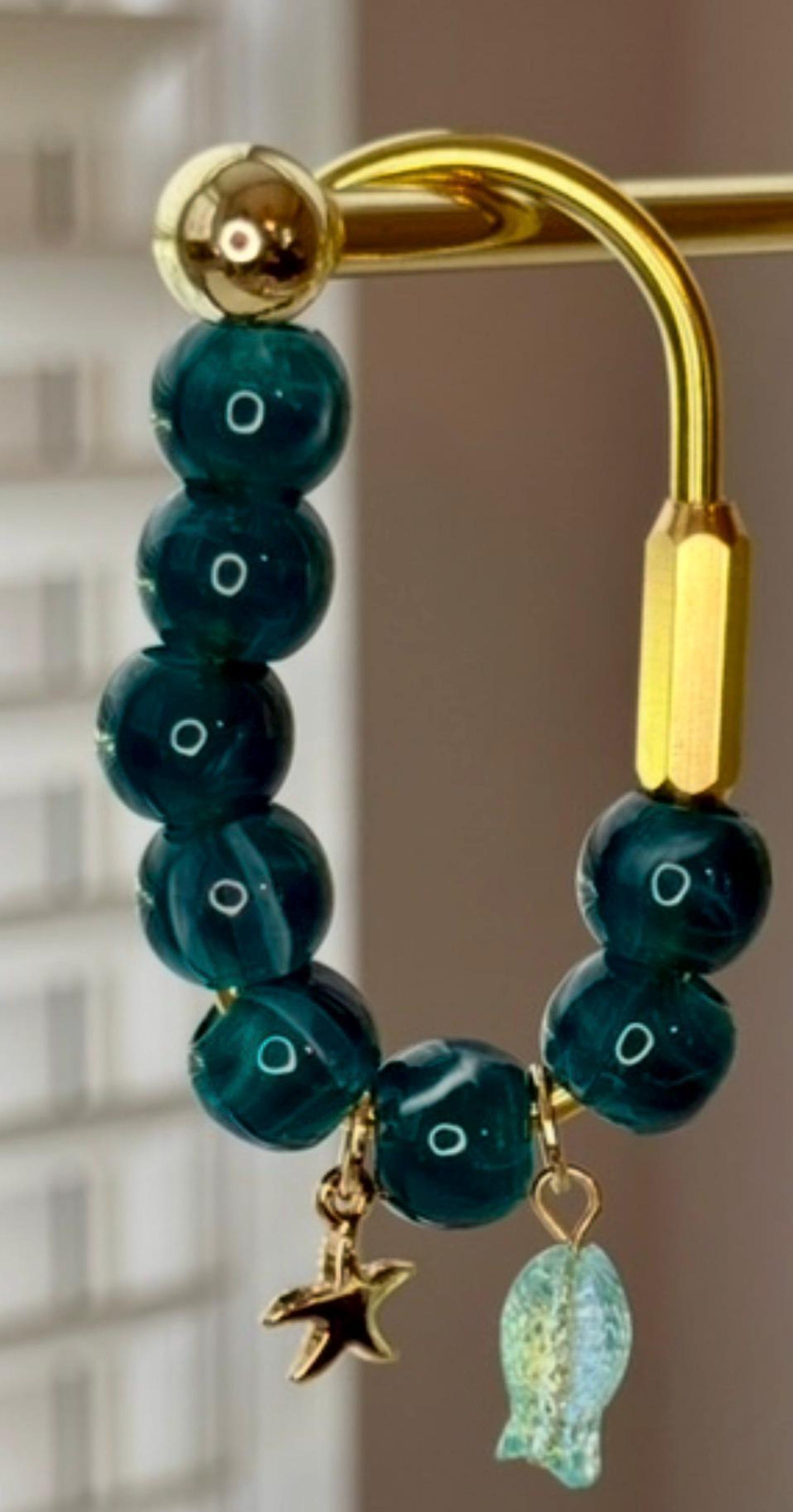 Gold carabiner bag charm with teal glass beads, a gold starfish charm, and a seashell charm